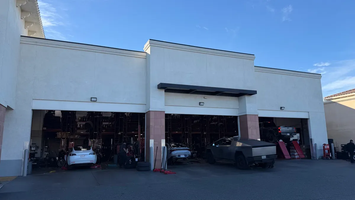 Exterior view of America's Tire service bays with Tesla Cybertruck and Model 3 inside.