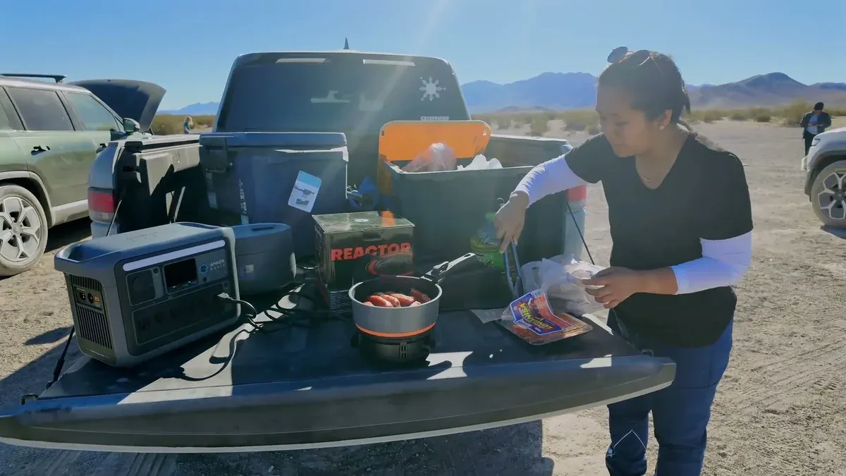 Camp table in the desert with an Anker power station running a cooking pot next to the Rivian
