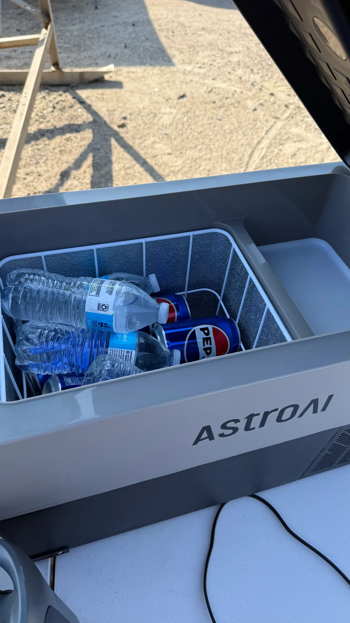 Inside the AstroAI portable refrigerator stocked with water bottles and cans of Pepsi