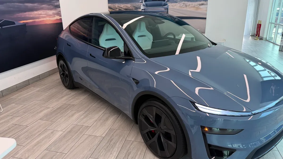 Frost Blue Model Y Performance elevated view showing panoramic glass roof and white interior