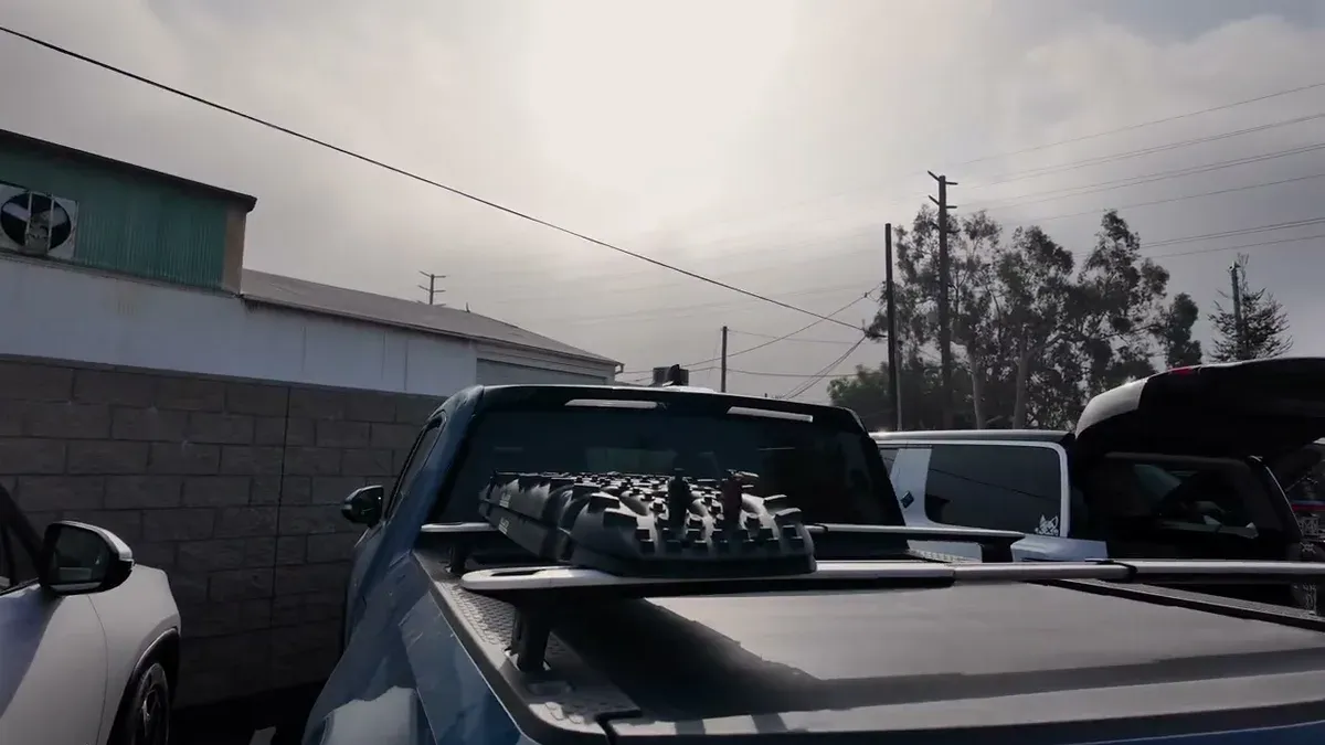 Blue Rivian R1T with recovery boards mounted on the bed cover