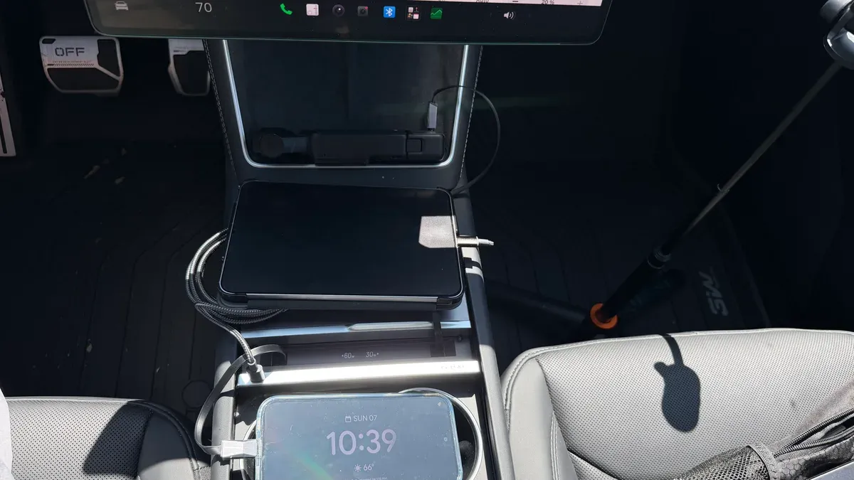 Tablet and phone charging from the Hansshow console hub with cables extended across the center tray
