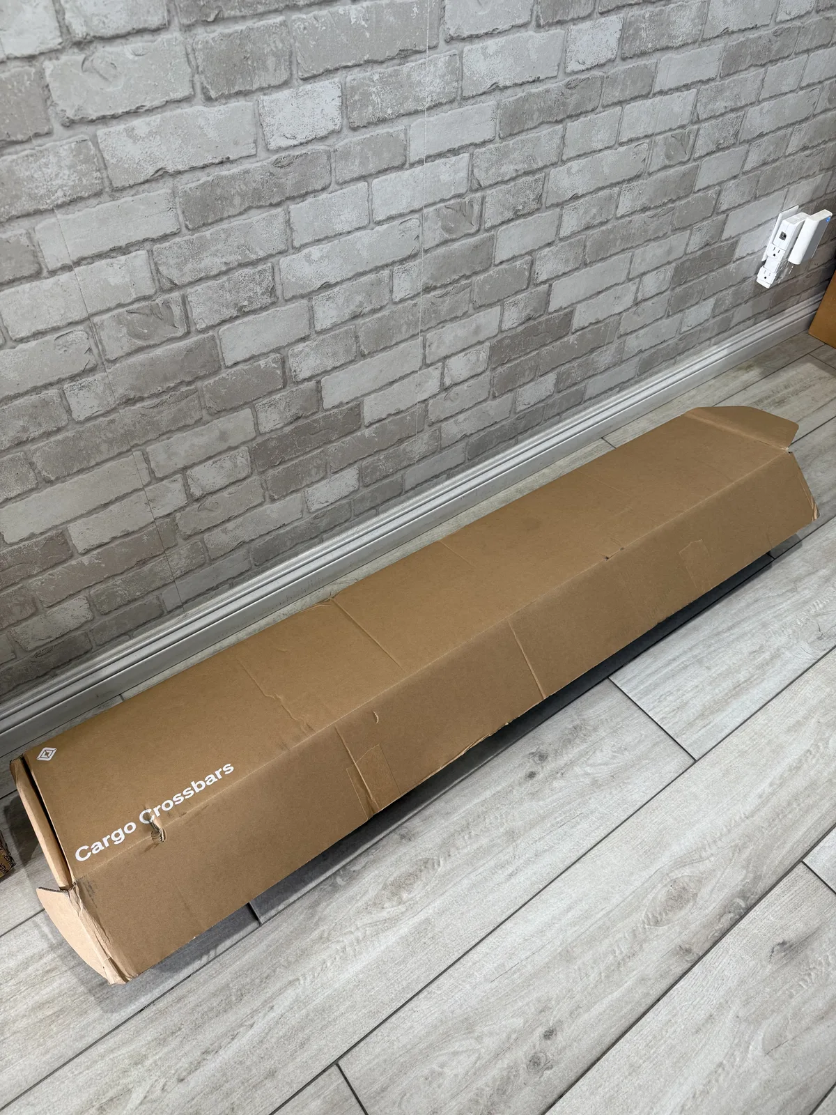 Unopened Rivian cargo crossbars box on a tile floor