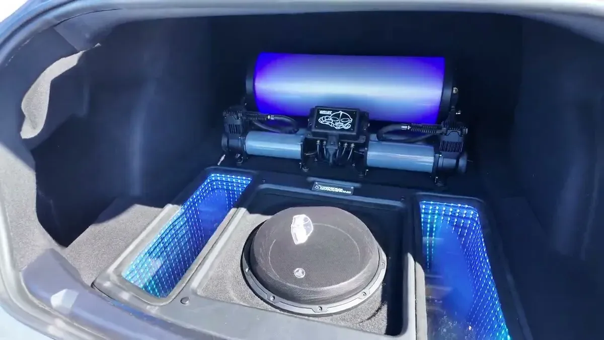 Custom trunk in Marvin's bippu Model 3 showing air suspension tank with blue LED lighting, subwoofer, and infinity mirror panels at EV Fest 2026