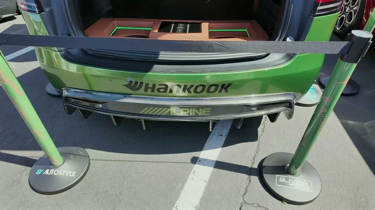 Rear view of George's custom green Model X with Alpine and Hankook branding, trunk open showing the sound system
