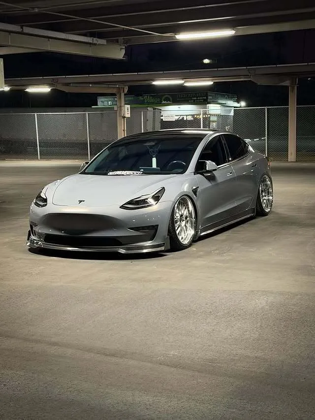 Marvin's custom Model 3 with chrome wheels and front splitter in a parking garage at night