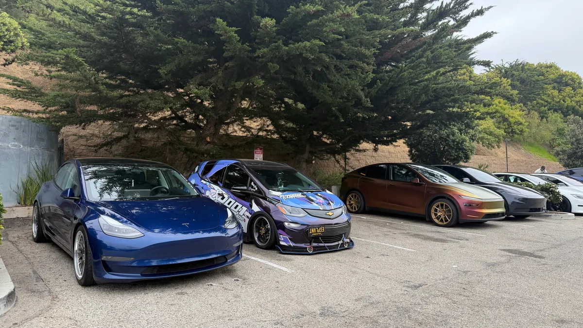 A Chevy Bolt EV parked alongside modified Teslas in the lot