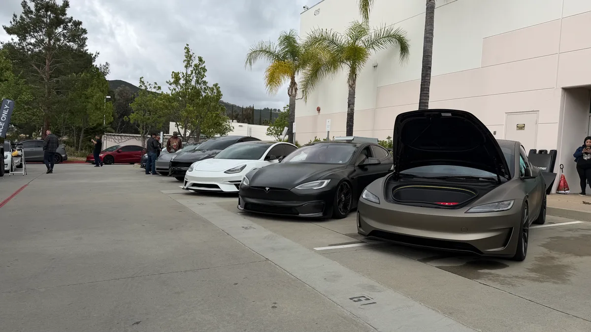 Row of custom Model S and other EVs with frunks open.