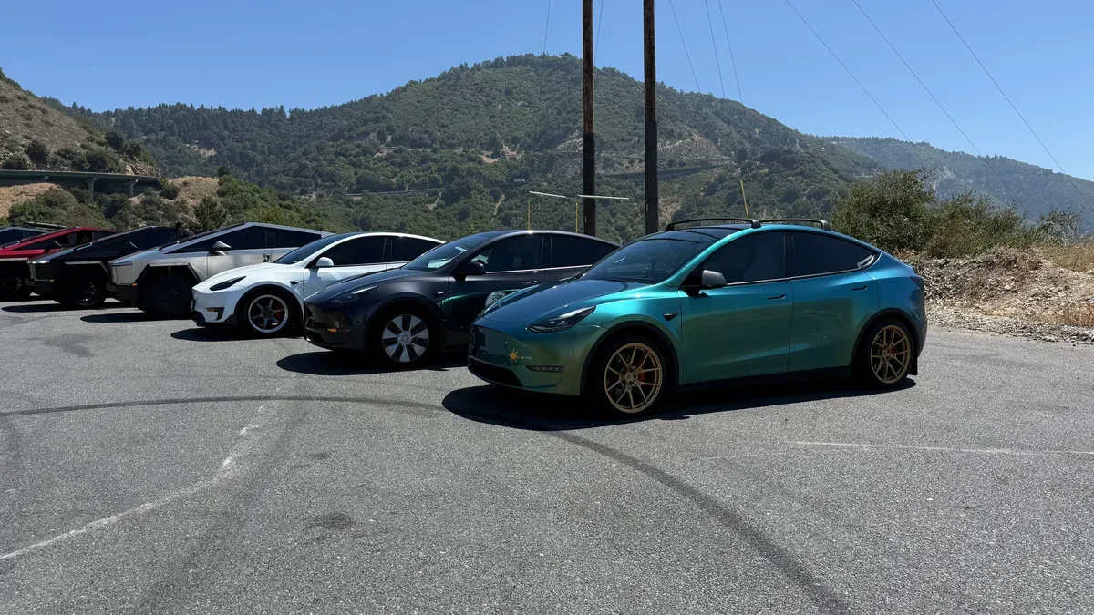 Close-up of custom-wrapped Tesla vehicles at the TeslaRuns gathering including a teal-to-gold wrapped Model Y and Cybertruck