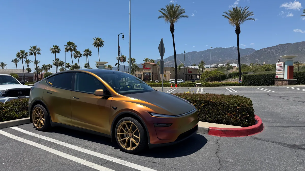 Custom-wrapped Tesla Model Y Juniper with gold wheels parked under palm trees in Southern California