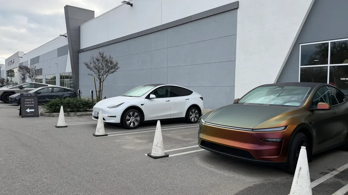Front view of the wrapped Model Y Juniper at the service center, with service check-in signs visible.