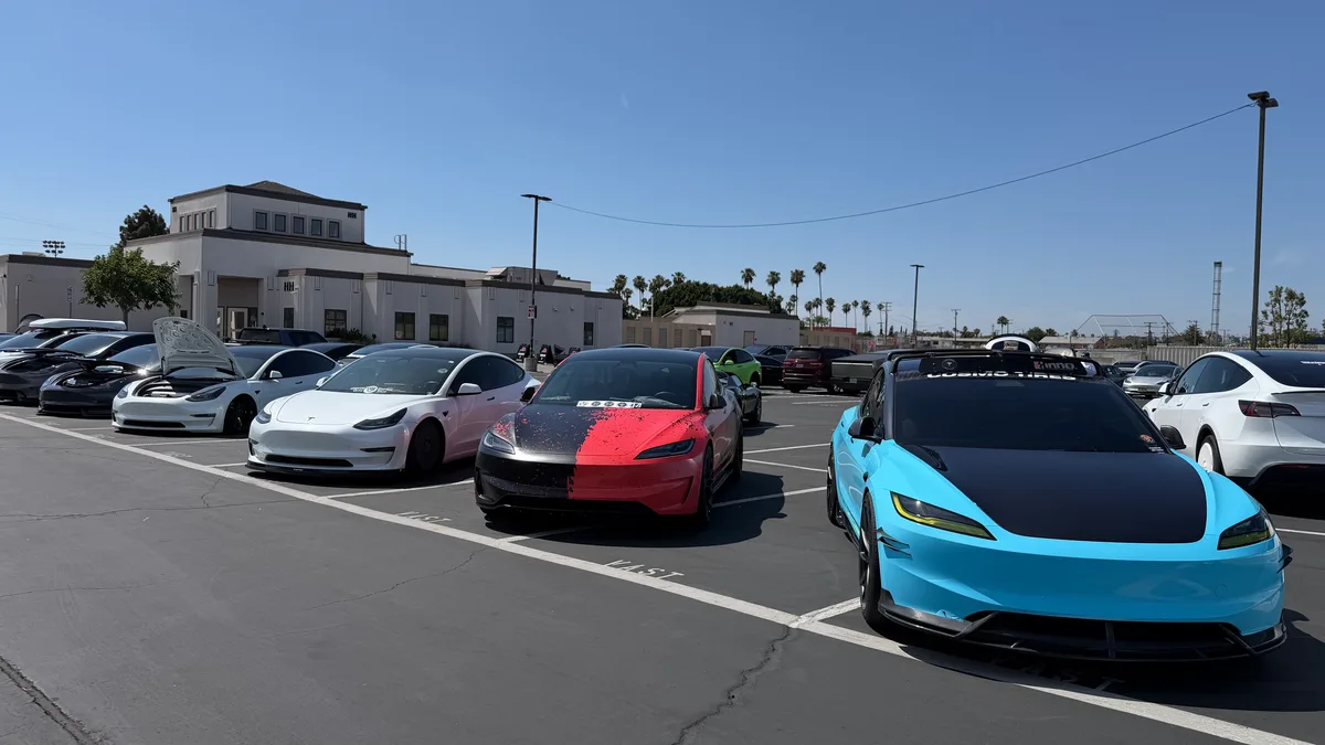 Row of customized Tesla Model 3s including a red and black split design at EV Fest 2026.
