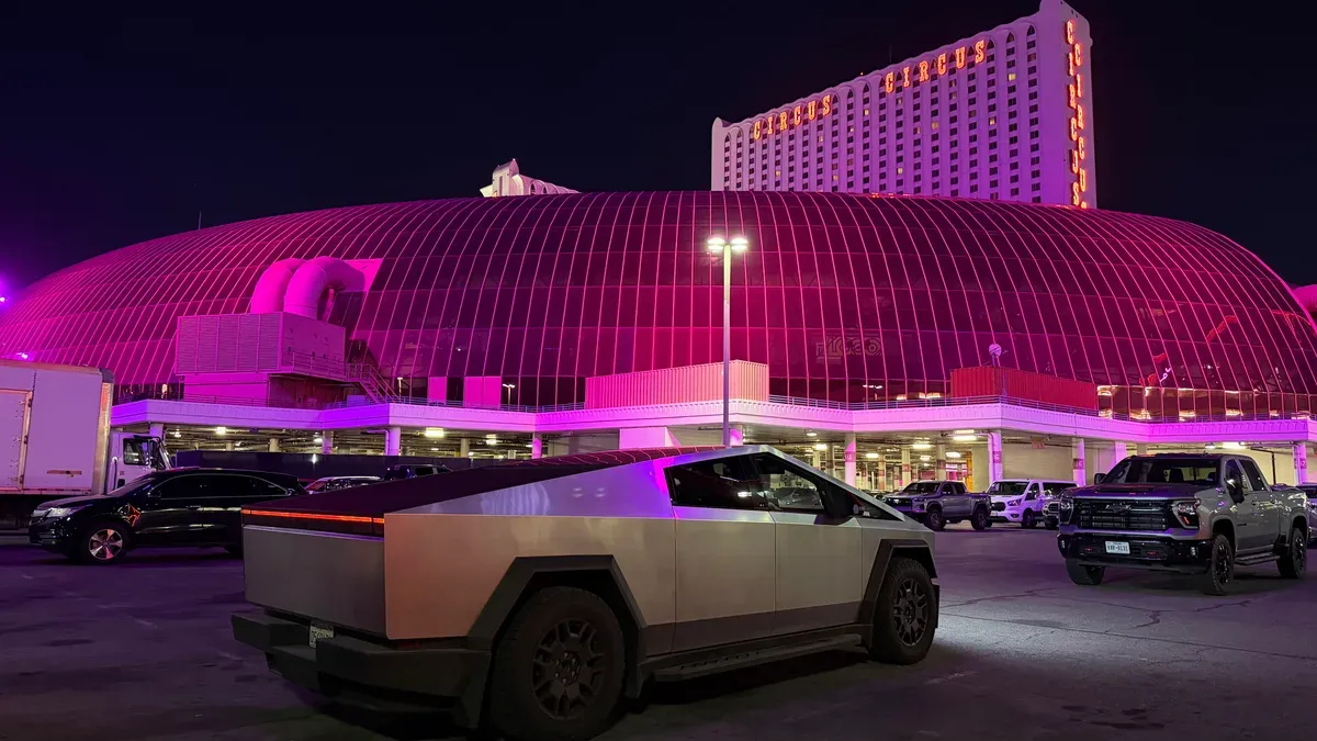 Tesla Cybertruck parked at night in front of the pink-lit Adventuredome at Circus Circus.