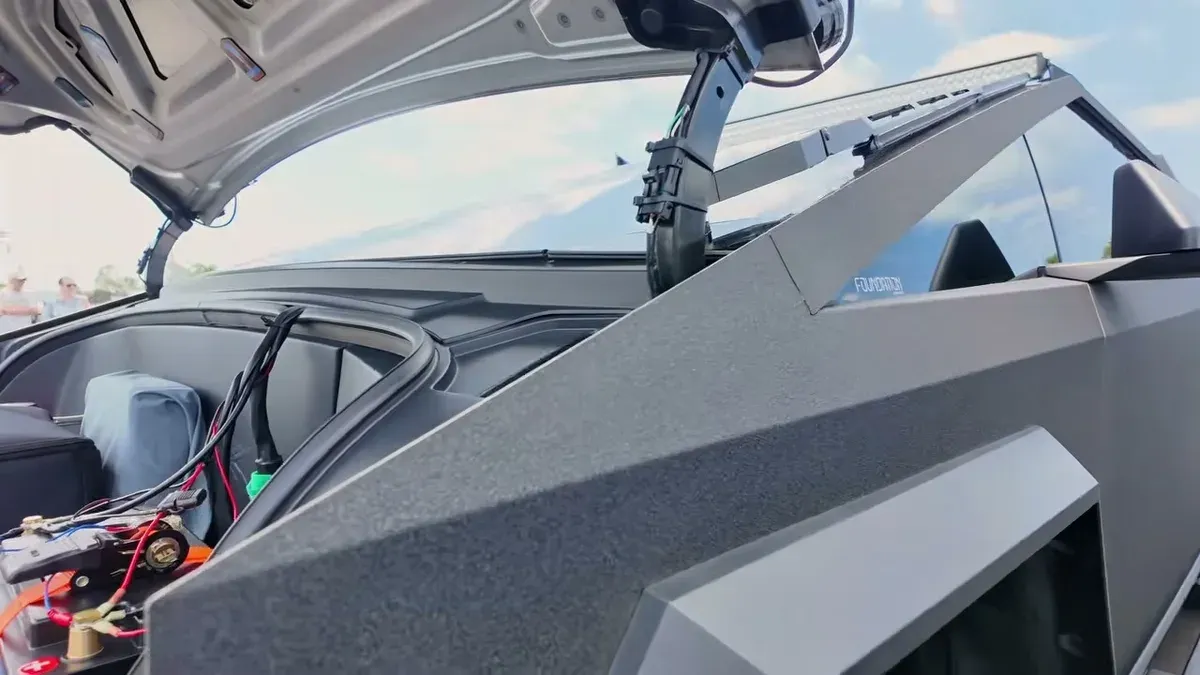 Matte black Tesla Cybertruck frunk open, showing wiring and roof light bar accessories