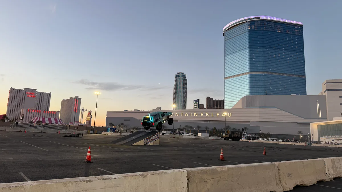 Custom truck launching off a ramp in a parking lot with Fontainebleau Las Vegas in the background at dusk