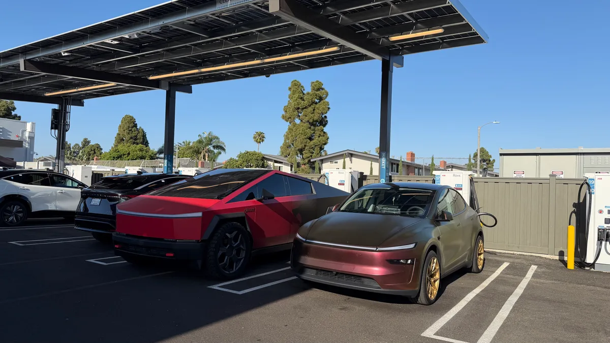 Red Cybertruck and Lucid Air charging at a solar-covered Rove EV station in Costa Mesa.