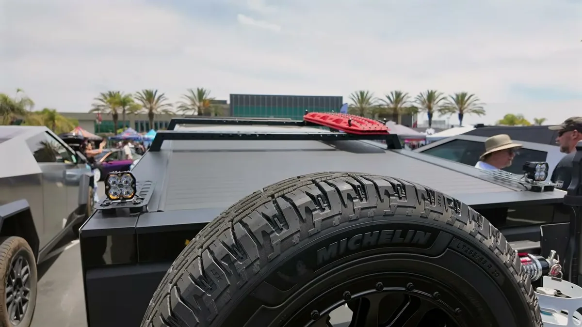 Michelin spare tire on Cybertruck rear with red recovery boards on roof rack