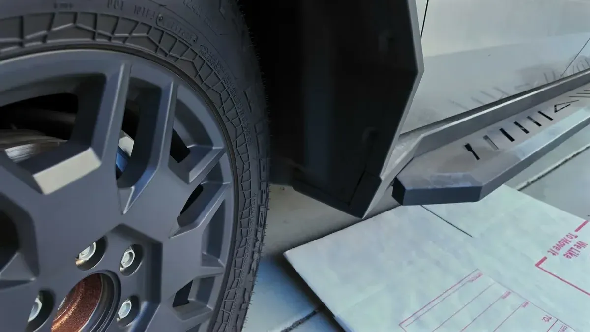 Close-up of Tesla Cybertruck front wheel and side, showing area for mud flap installation.