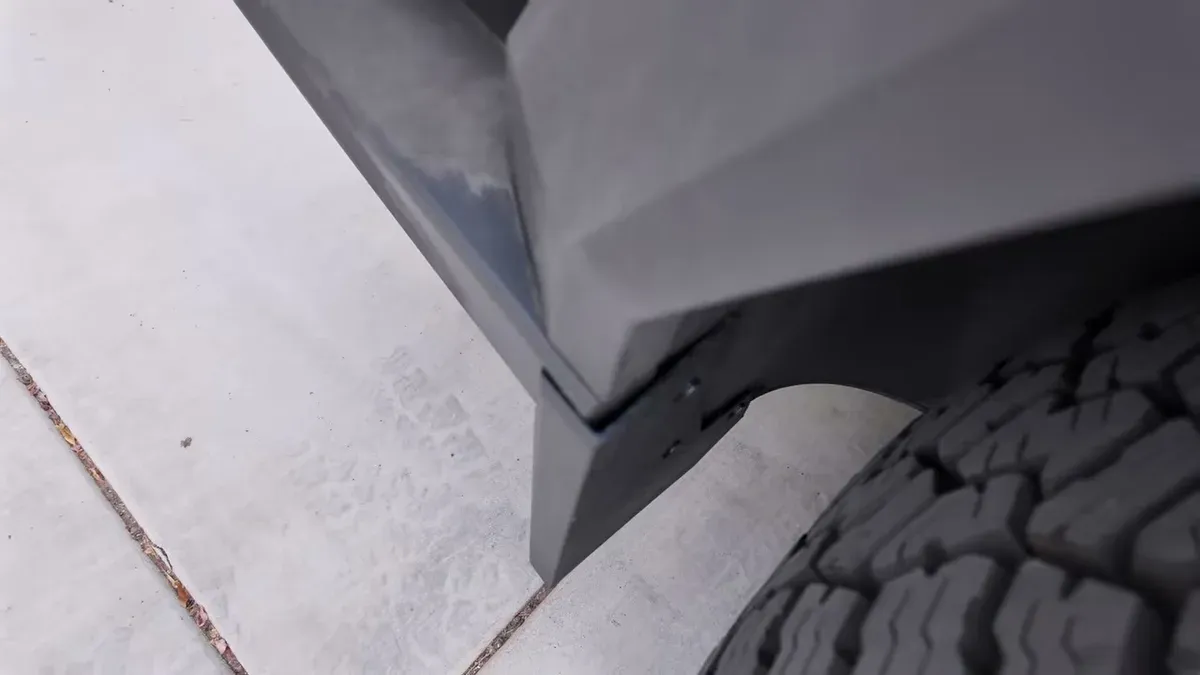 Close-up of newly installed black mud flap on Tesla Cybertruck, showing integration with body and tire.