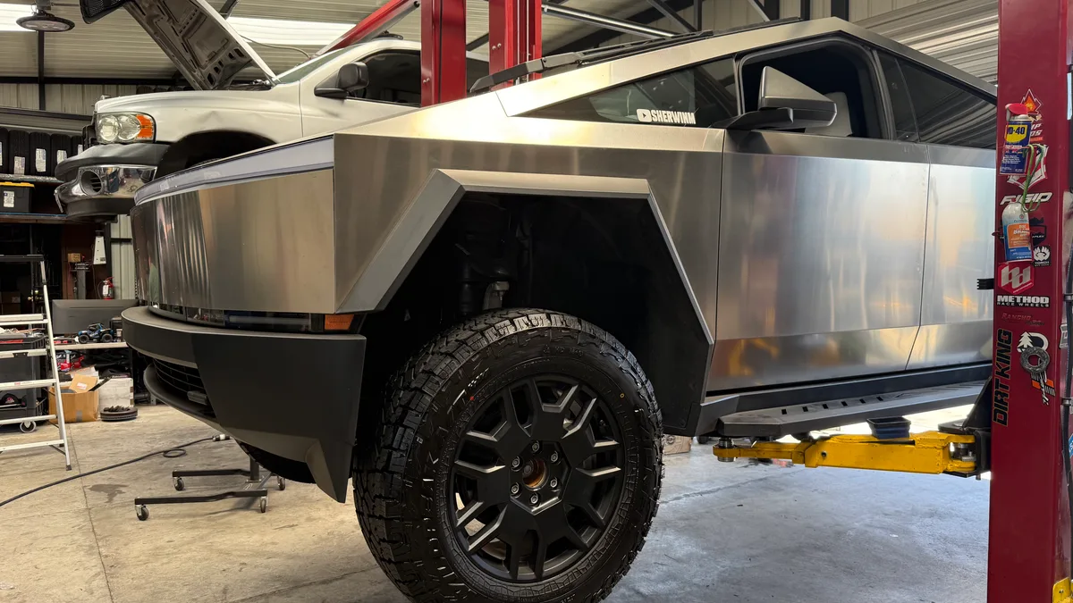 Front passenger side of a lifted Tesla Cybertruck with new black wheel and Falken Wildpeak A/T4W tire.