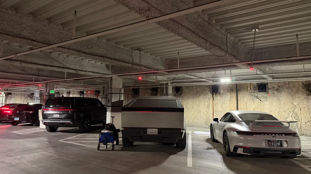 Tesla Cybertruck, Porsche 911, and Rivian R1S in underground garage.