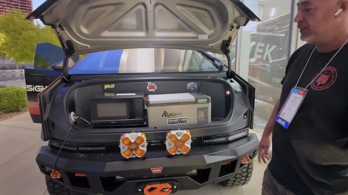 Cybertruck tailgate open showing Alpicool fridge, microwave, and amber auxiliary bumper lights