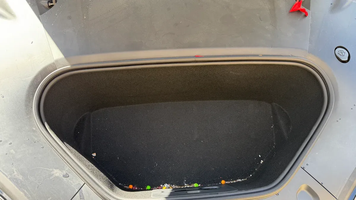 Overhead view of the dirty 2026 Model S loaner frunk, with debris and a Tootsie Roll left by a previous user.
