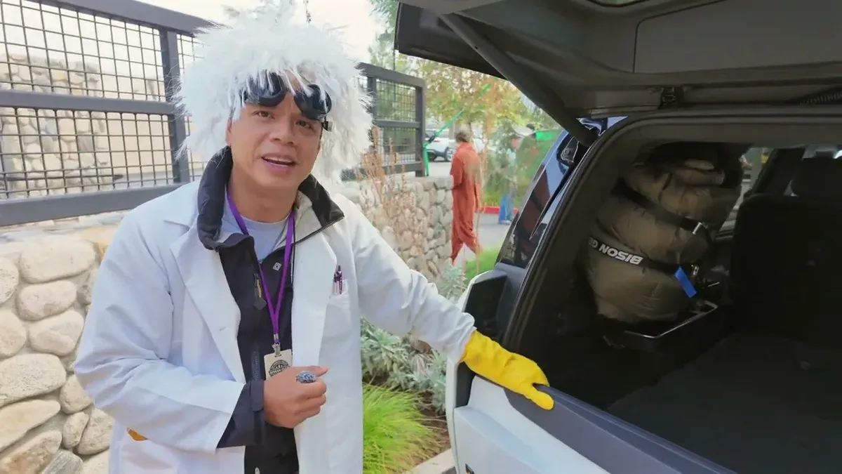Person dressed as Doc Brown standing next to the open tailgate of a white Rivian R1S with Bison sleeping bag visible inside