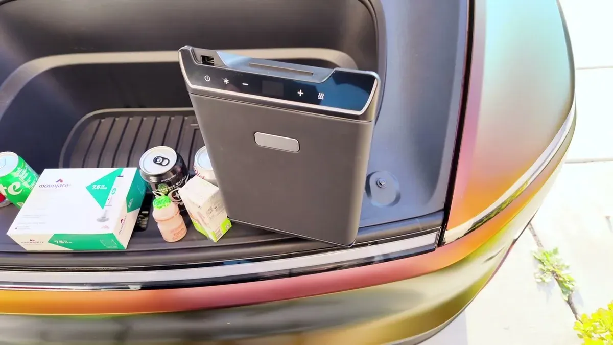 Close-up of the Teslaunch fridge sitting in the frunk surrounded by drinks, a Mounjaro box, and a small bottle