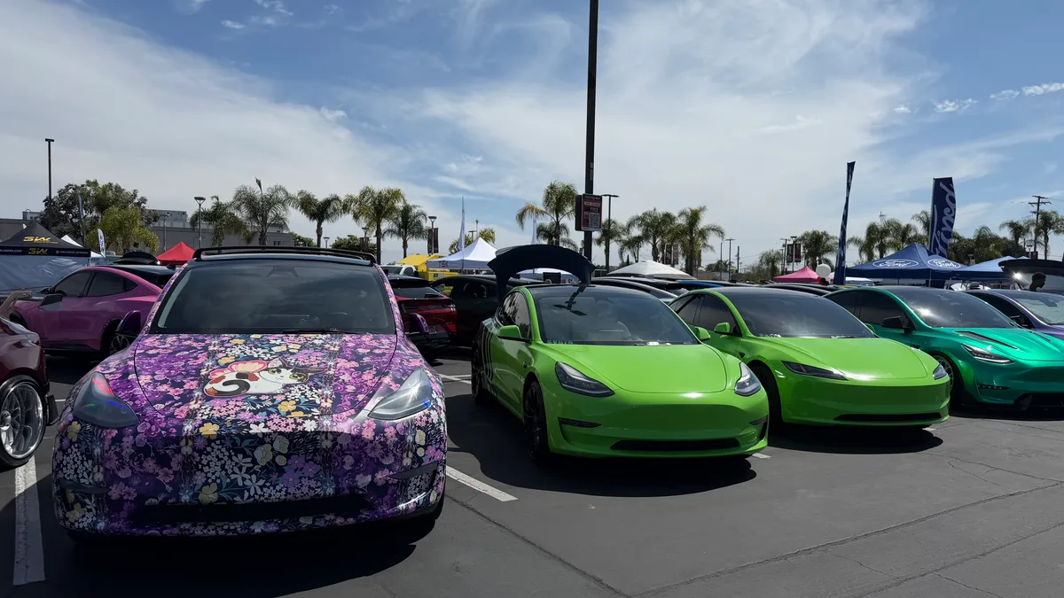 Purple floral-wrapped Tesla Model Y next to bright green Teslas at EV Fest 2026.
