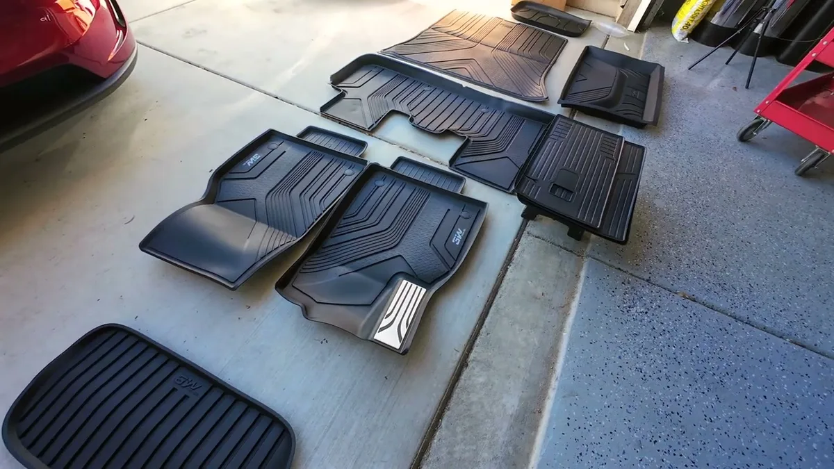 Full set of black 3W floor mats including front, rear, and cargo liners laid out on garage floor
