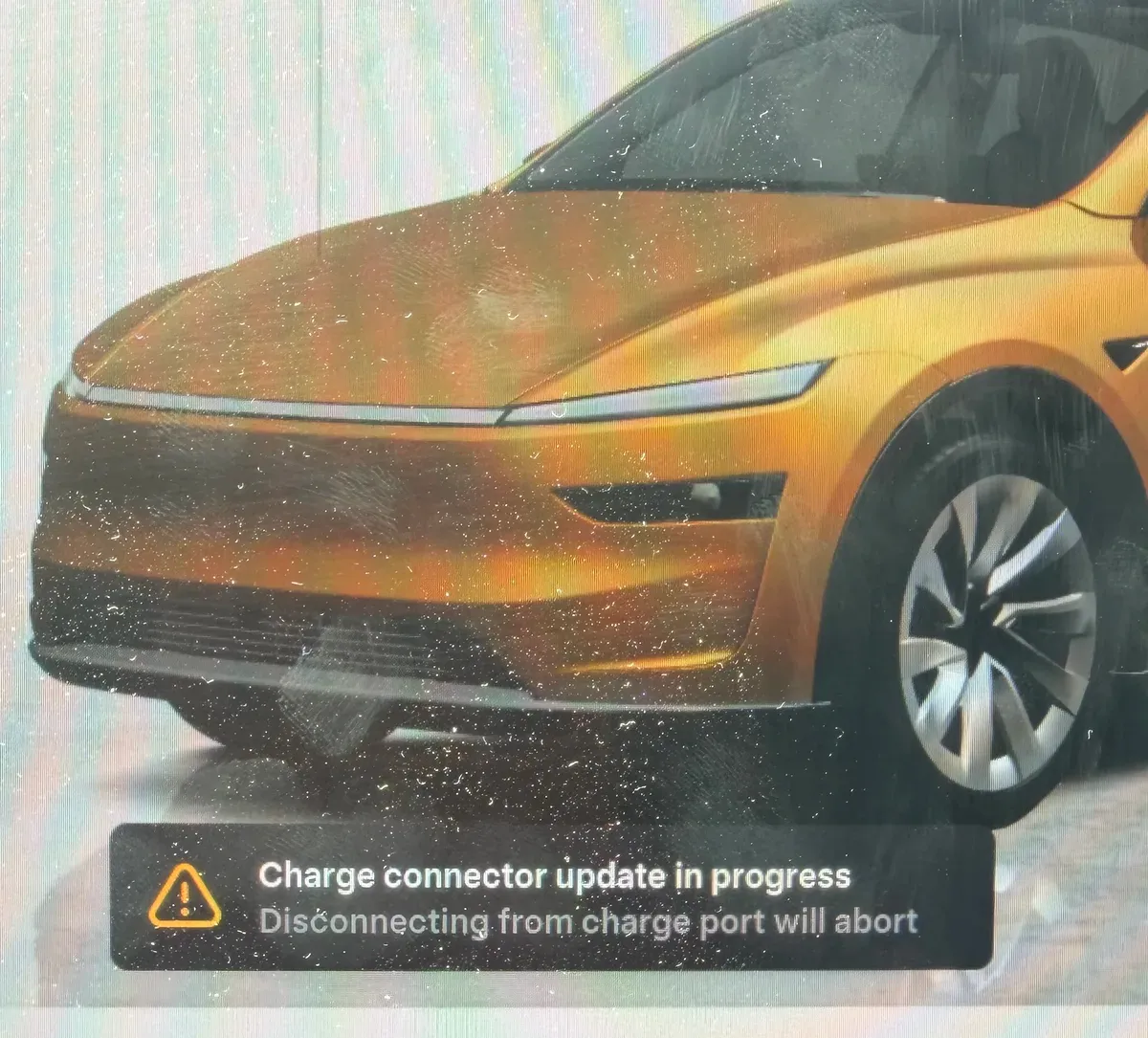 Tesla touchscreen showing Charge connector update in progress, with a warning that disconnecting from the charge port will abort it