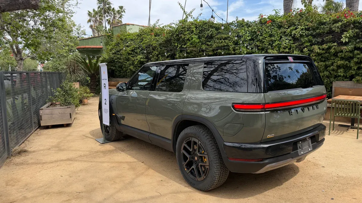 Launch Green Rivian R2 SUV parked on a dirt path at the Venice Block Party event.