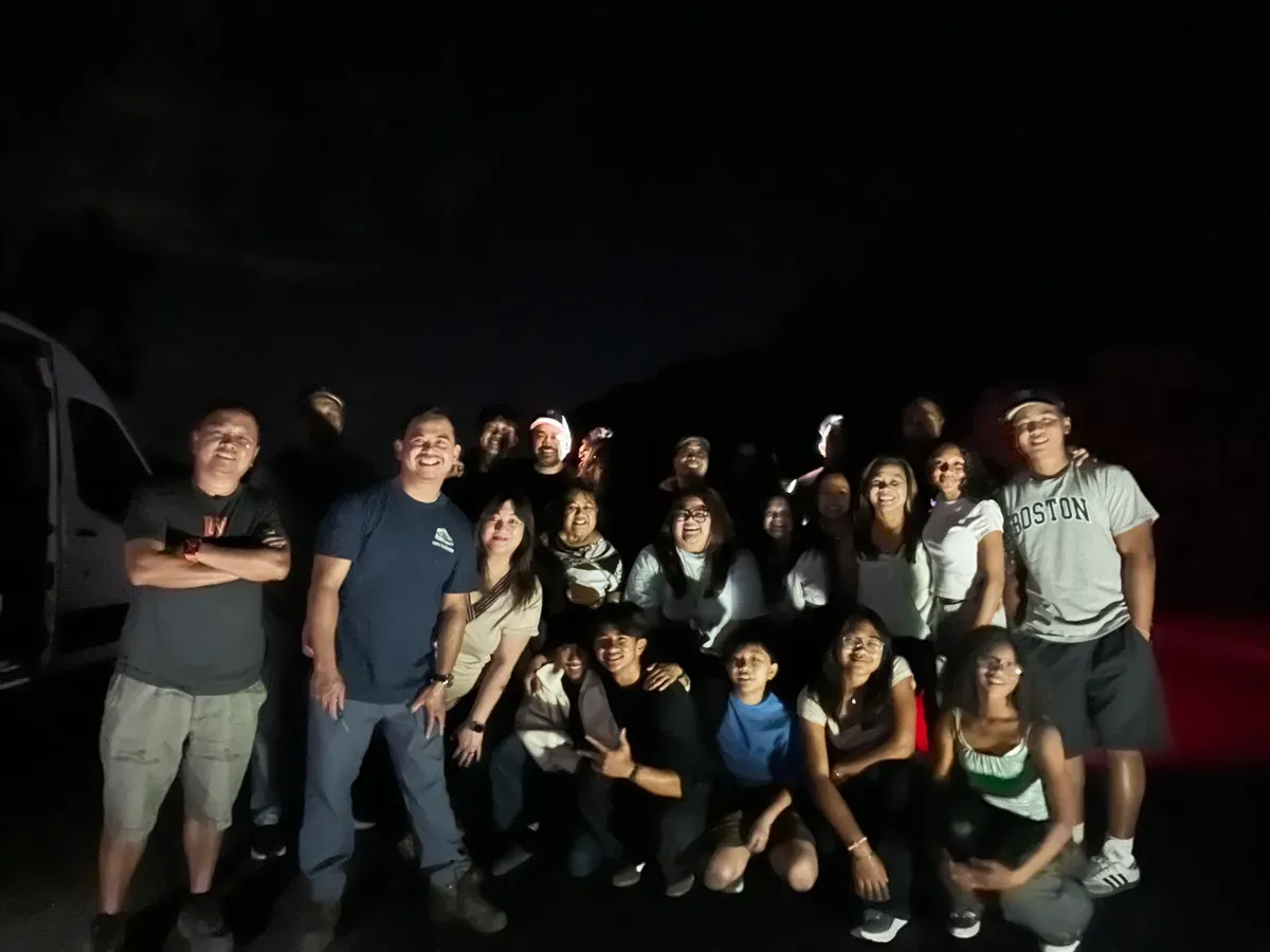 Large group of friends posing for a photo at night in Joshua Tree
