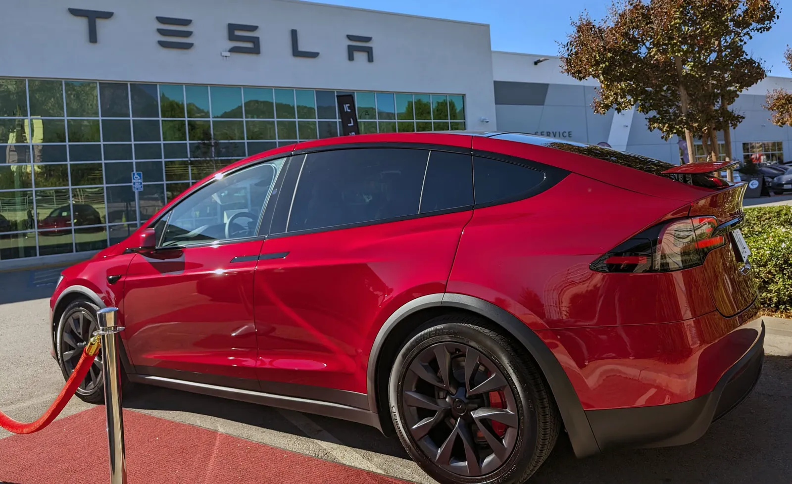 Model X Plaid Ultra Red driver side in front of Tesla