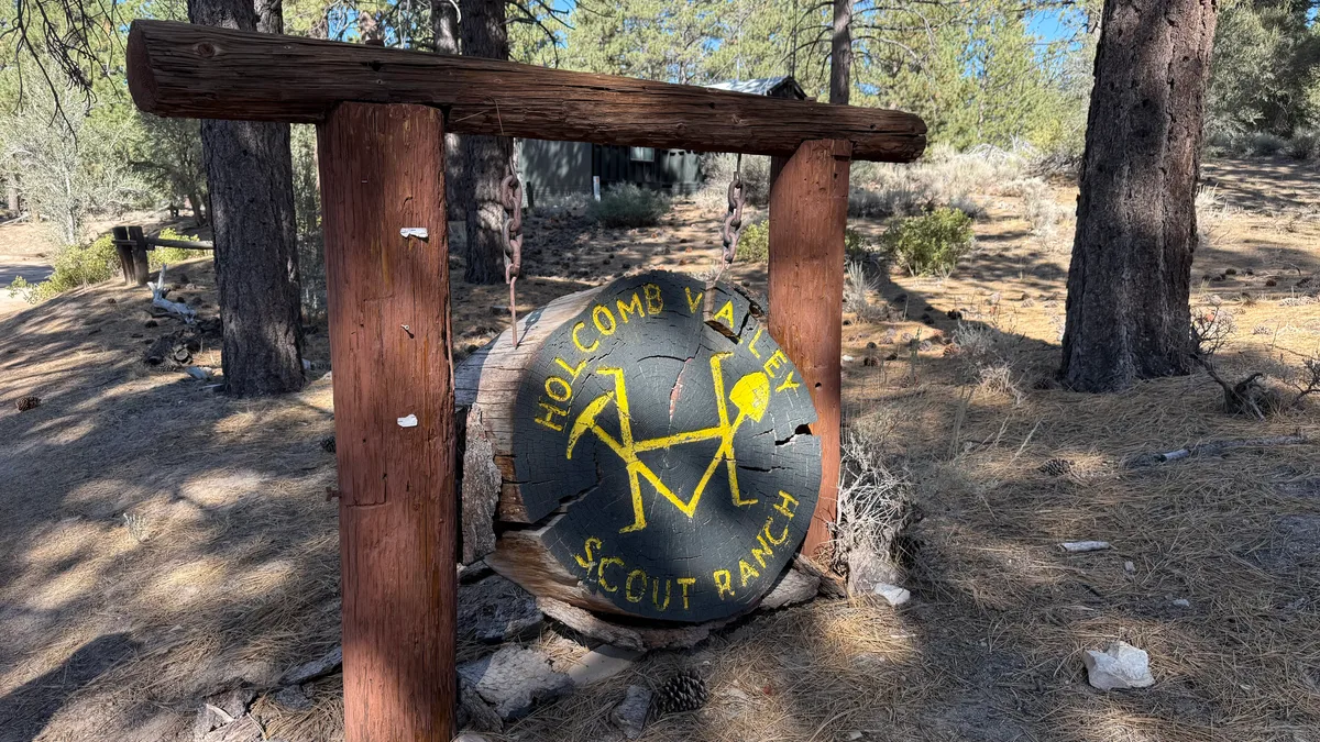 Rustic Holcomb Valley Scout Ranch sign on a log frame in the pine forest
