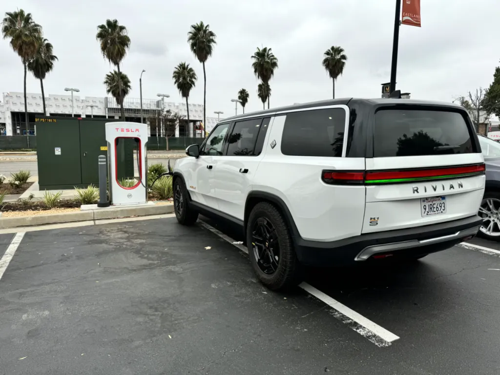 Glacier White Gen 1 Rivian R1S using a Tesla supercharger
