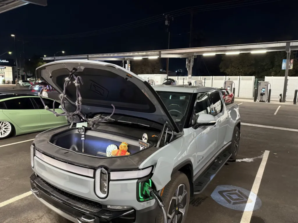 Rivian R1T with frunk open at Rove charging during Halloween