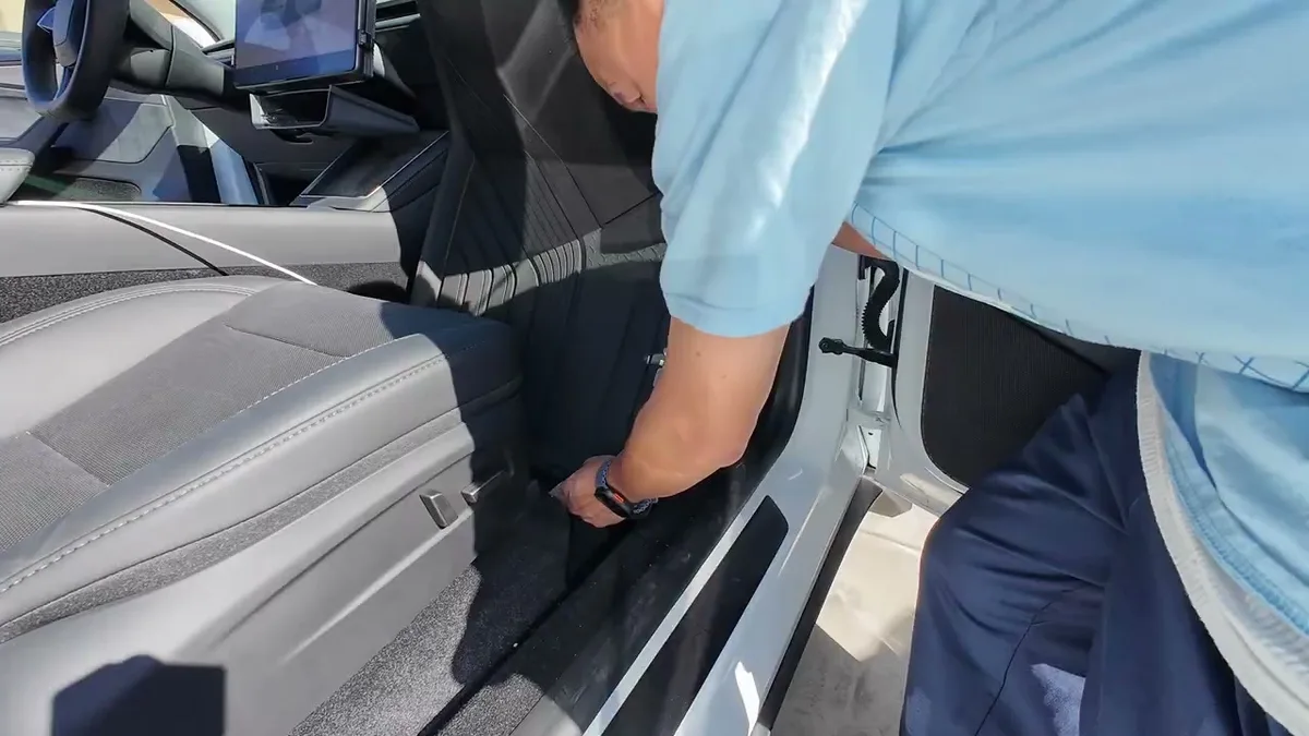 Close-up of hands pressing a 3W floor mat into the passenger footwell of a white Tesla