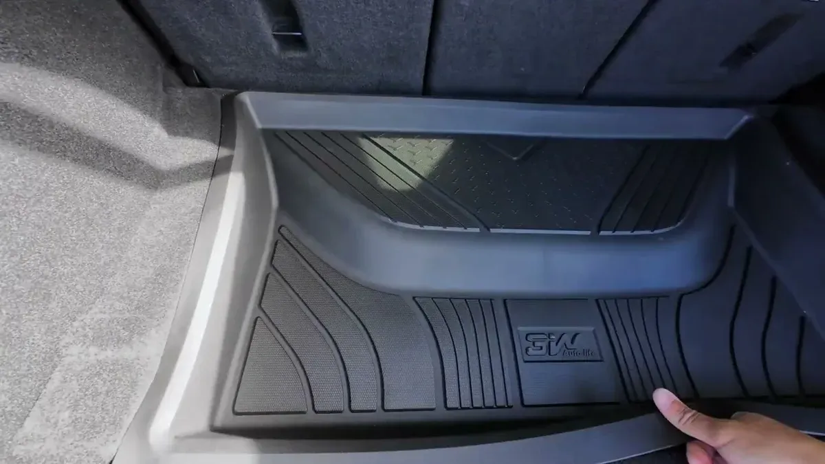 Close-up of black 3W custom-fit trunk liner being pressed into the cargo area of a Tesla
