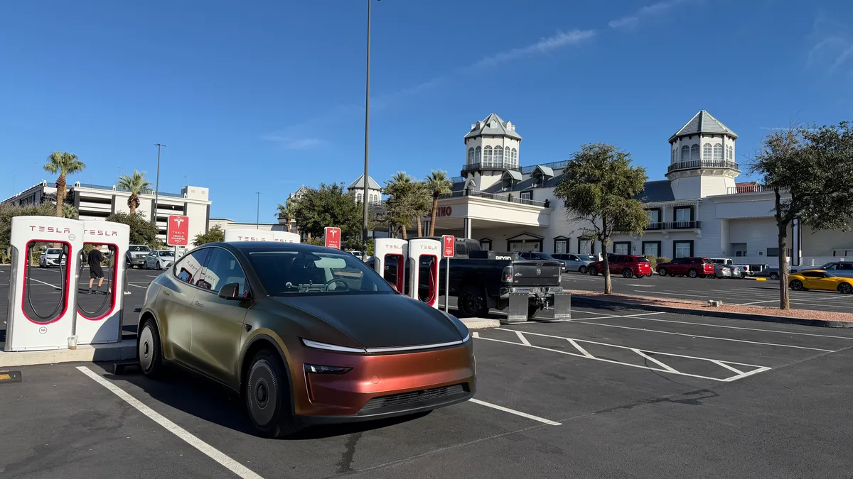 Wrapped Model Y Juniper parked at Tesla Supercharger stalls in Primm with a white casino building in the background