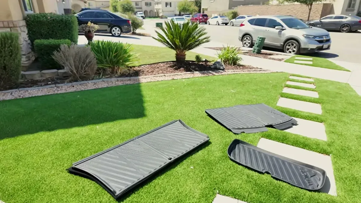 Jowua floor mats and liners laid out on grass to flatten in the sun.