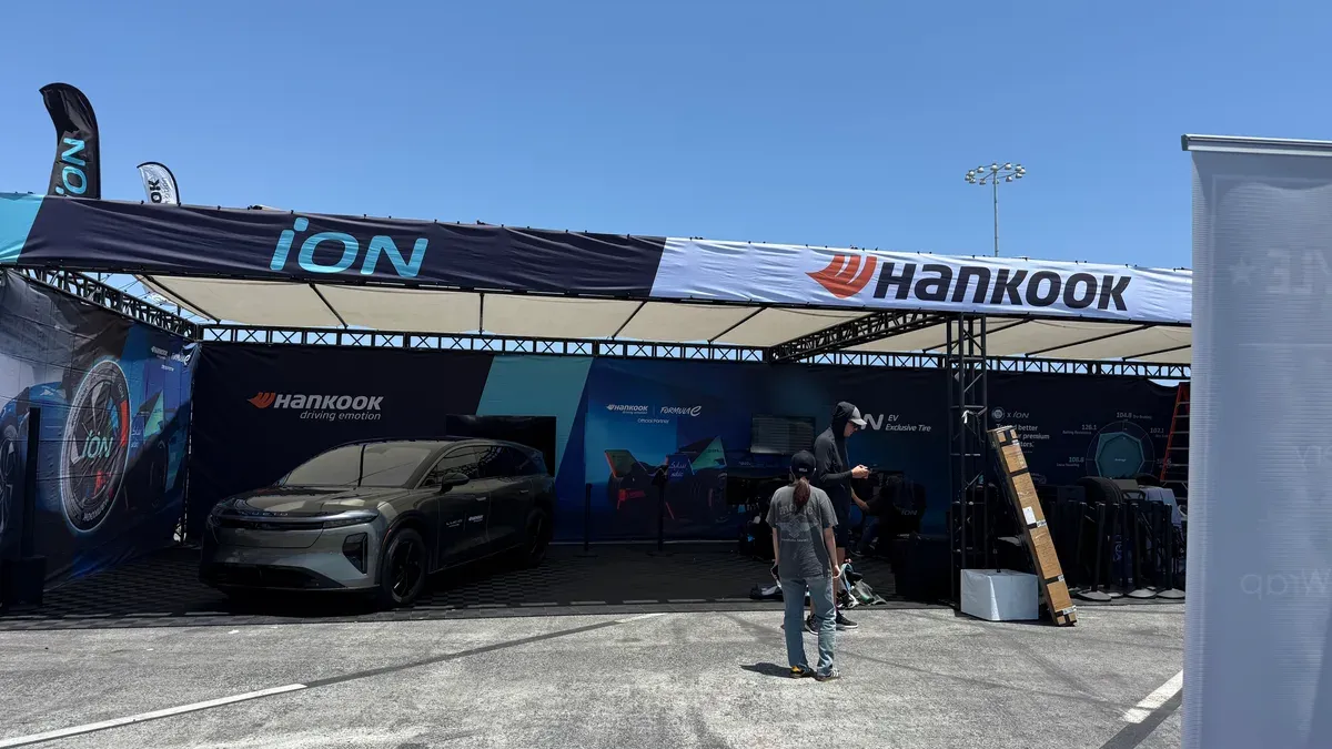 Dark grey Lucid Air EV displayed under a large Hankook ION banner at Electrify Expo with event staff nearby