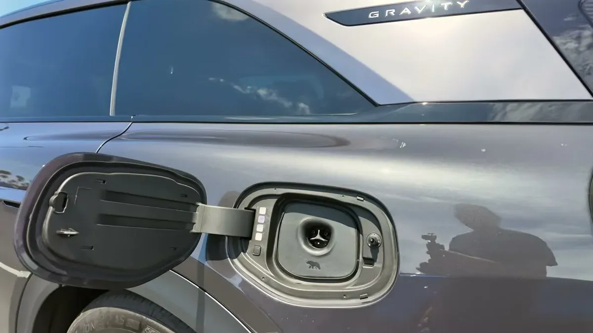 Lucid Gravity exterior showing open charging port and GRAVITY badge on the vehicle door.
