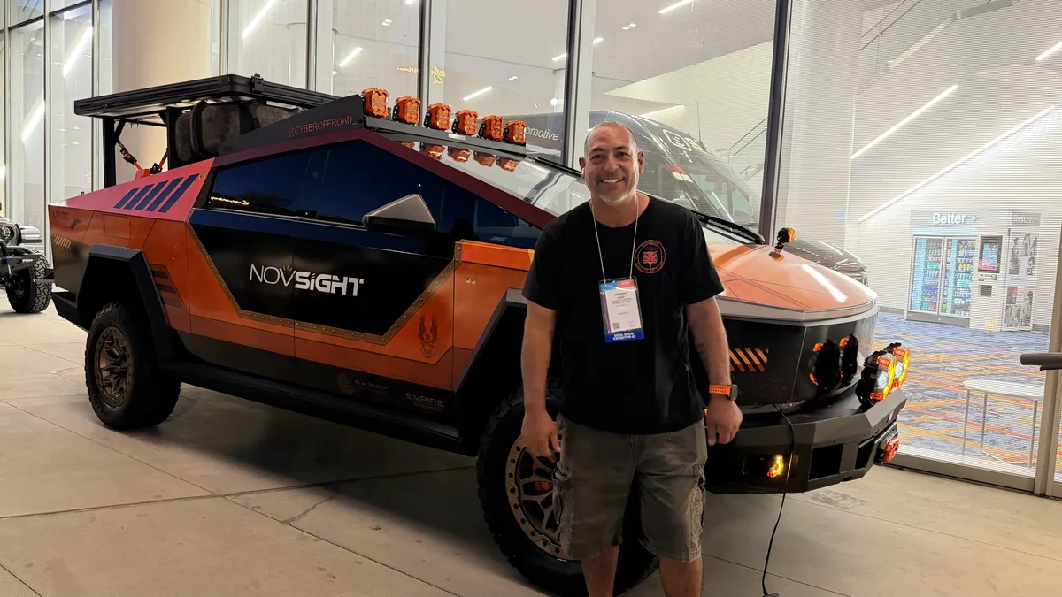 Sherwin standing with Jerry's custom orange Cybertruck at SEMA 2025