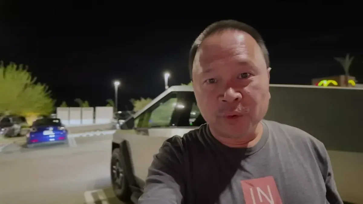 Man speaking to camera with Cybertruck visible in background at night