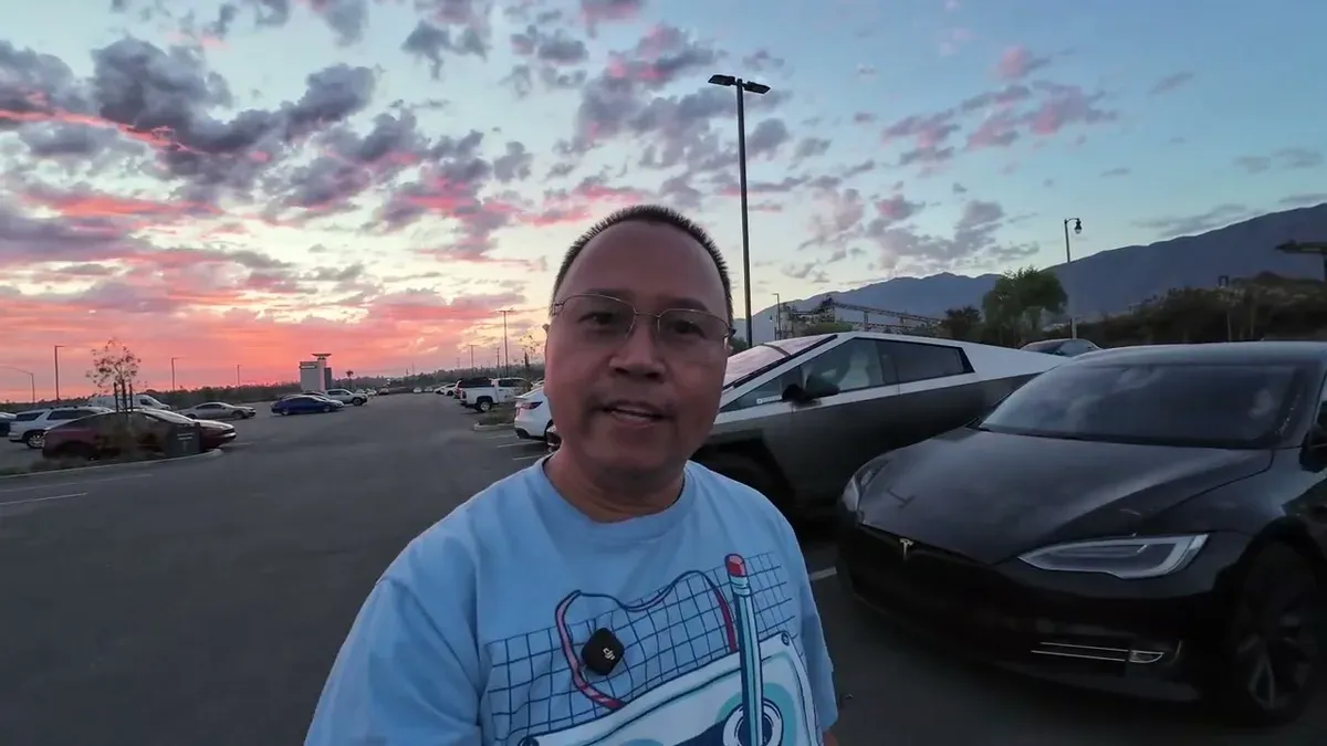 Man standing in service lot at sunset with Cybertruck and Tesla Model S visible in the background