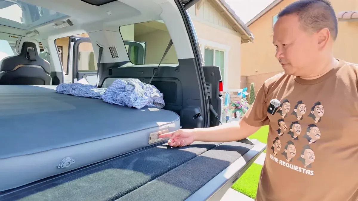 Sherwin pointing to the deflation valve on the EVBase air mattress inside the Rivian R1S cargo area