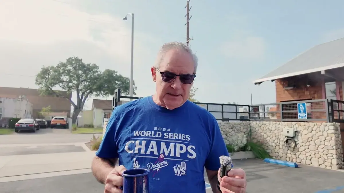 Man in a Dodgers World Series Champs shirt holds a mug at the meetup