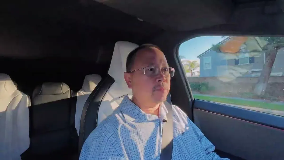 Man in plaid shirt driving toward the Upland Tesla service center on a clear morning